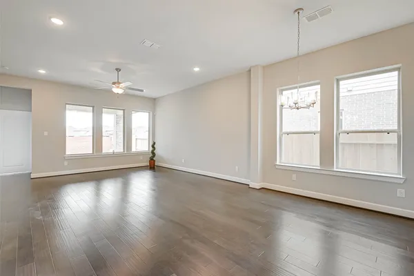 an empty room with wooden floor and windows with curtains