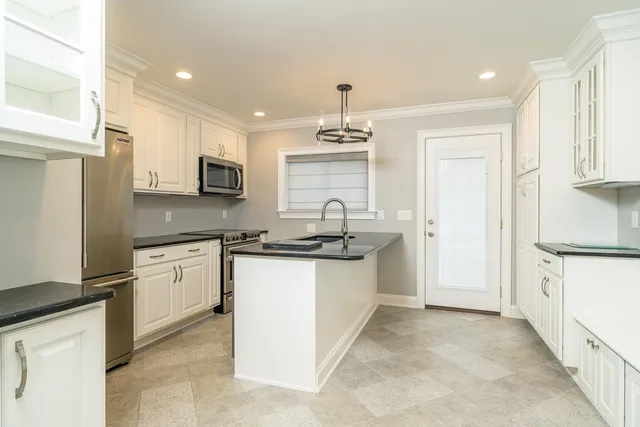 a kitchen with kitchen island granite countertop a sink appliances cabinets and counter space