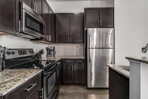 a kitchen with stainless steel appliances granite countertop a refrigerator stove and microwave