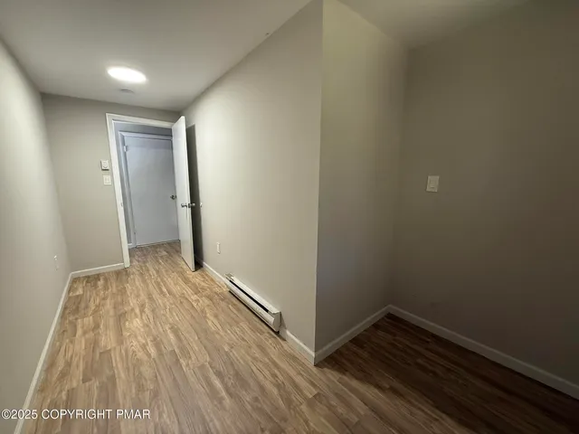 an empty room with wooden floor chandelier fan and windows