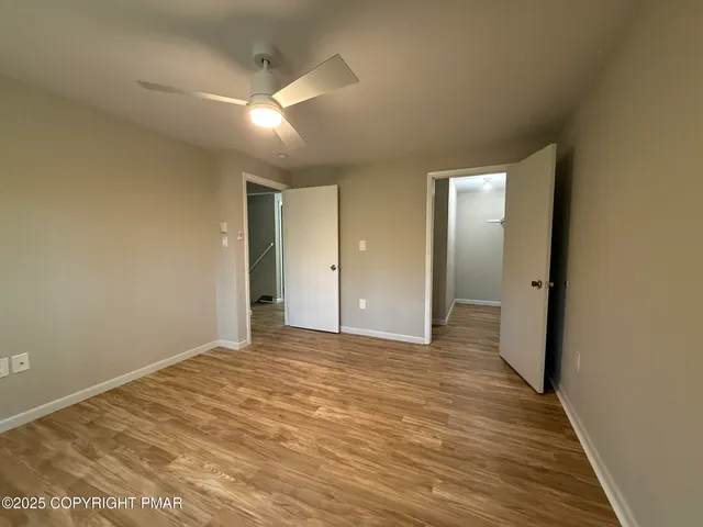 an empty room with wooden floor fan and windows
