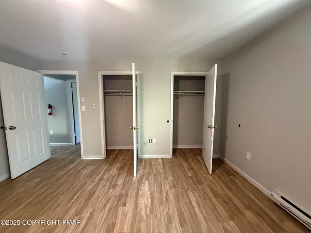 an empty room with wooden floor cabinet and windows