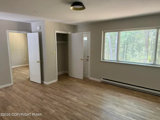 an empty room with wooden floor and windows