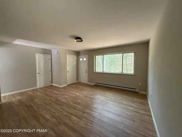 a view of an empty room with wooden floor and a window