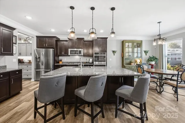 a kitchen with stainless steel appliances granite countertop a kitchen island hardwood floor sink stove dining table and chairs