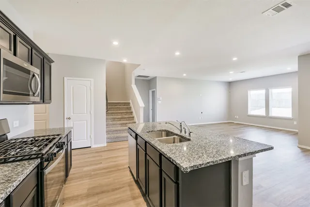 a kitchen with granite countertop kitchen island stainless steel appliances a sink stove and cabinets