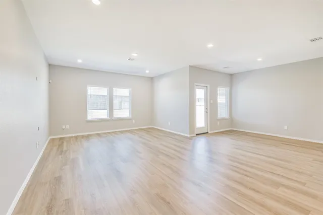 a view of an empty room with wooden floor and window