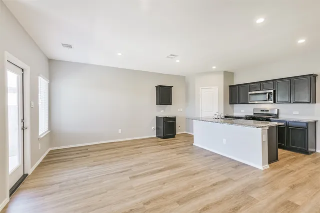 a large kitchen with a large counter top space stainless steel appliances and cabinets