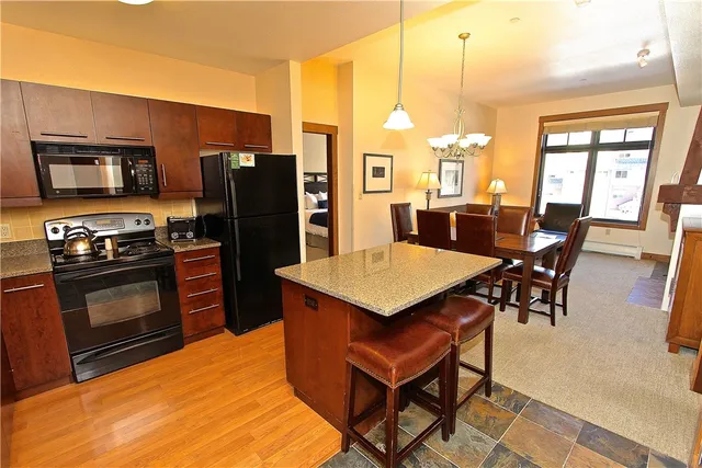a kitchen with stainless steel appliances kitchen island granite countertop a table chairs and a refrigerator