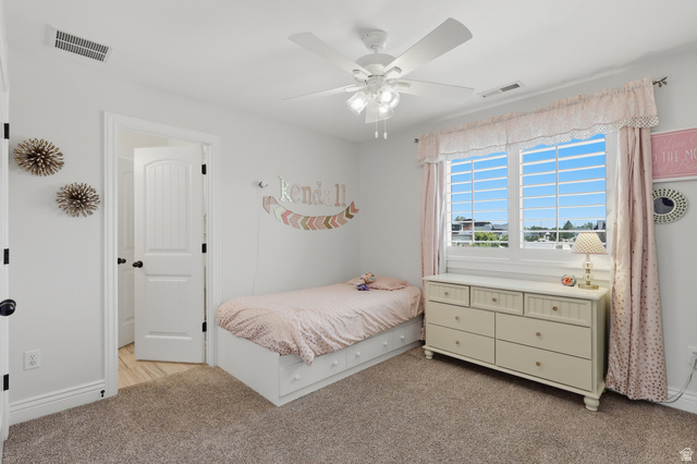 10676 Urban Rdg Cove South Jordan, UT 84095 - Photo 27 of 48 White-painted room featuring a large window with white muntins, light-colored carpeting, a white ceiling fan with integrated lighting, a white six-panel door with black hardware, and white baseboards