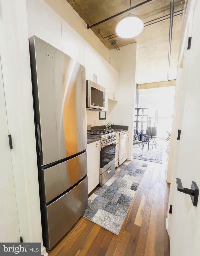 1300 N Street Northwest, Unit 713 Washington, DC 20005 - Photo 12 of 38 a kitchen with stainless steel appliances granite countertop a refrigerator a stove and a sink with wooden floor