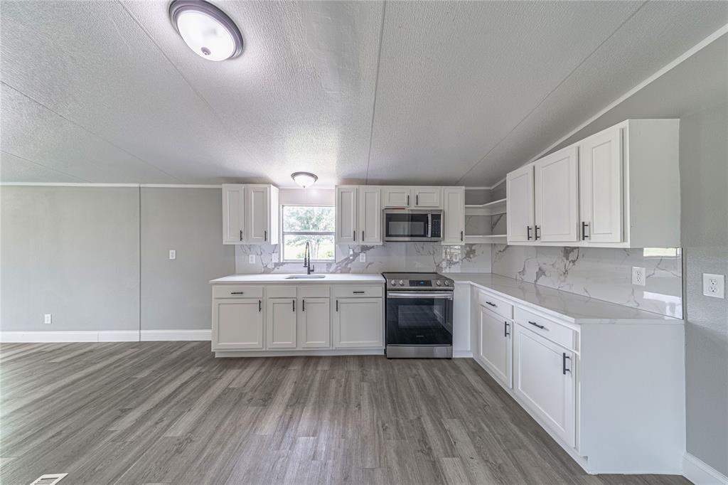 3055 Shanda Court Kaufman, TX 75142 - Photo 5 of 21 Kitchen with white cabinets, open shelves, appliances with stainless steel finishes, backsplash, and a textured ceiling