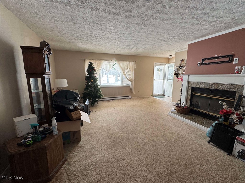 8631 Center Road Ashtabula, OH 44004 - Photo 7 of 25 Living area featuring a textured ceiling, a baseboard heating unit, carpet flooring, and a glass covered fireplace