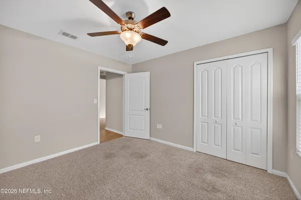 an empty room with a chandelier fan and windows