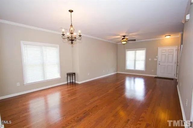 a view of an empty room with a window and wooden floor