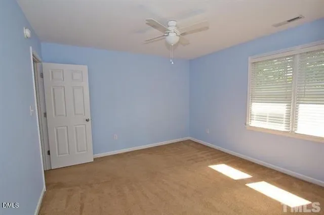 an empty room with a window and a fan