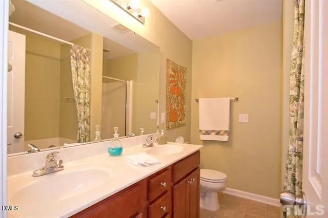 a bathroom with a double vanity sink toilet and a mirror