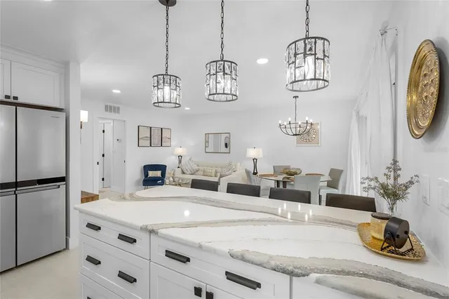 a kitchen island with stainless steel appliances granite countertop a sink and a refrigerator