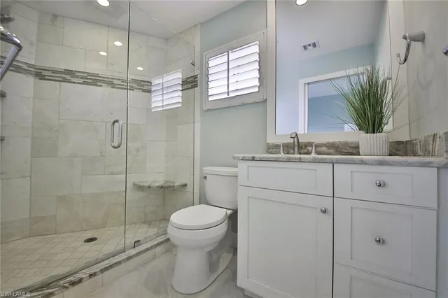 a bathroom with a shower sink vanity mirror and toilet
