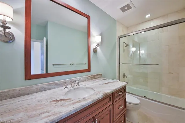 a bathroom with a granite countertop sink toilet and shower