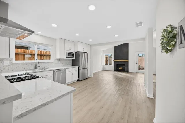 a kitchen with granite countertop a sink stainless steel appliances and window