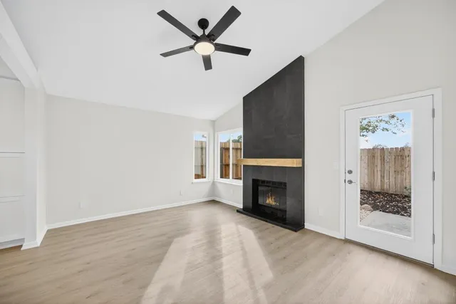a view of an empty room with wooden floor and a ceiling fan
