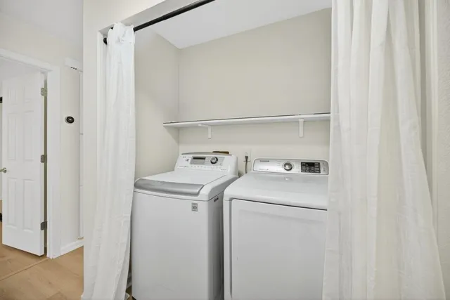 a view of a hallway with wooden floor and a bathroom