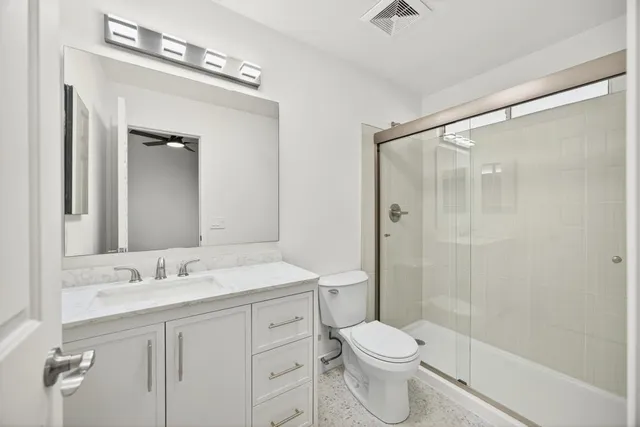 a bathroom with a double vanity sink toilet mirror and shower