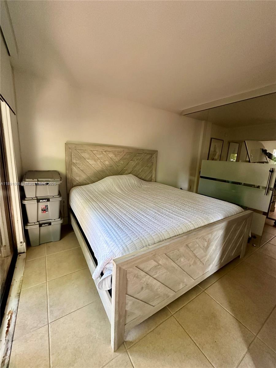 1650 Northeast 115th Street, Unit 102 Miami, FL 33181 - Photo 11 of 18 a bedroom with a bed and a night stand