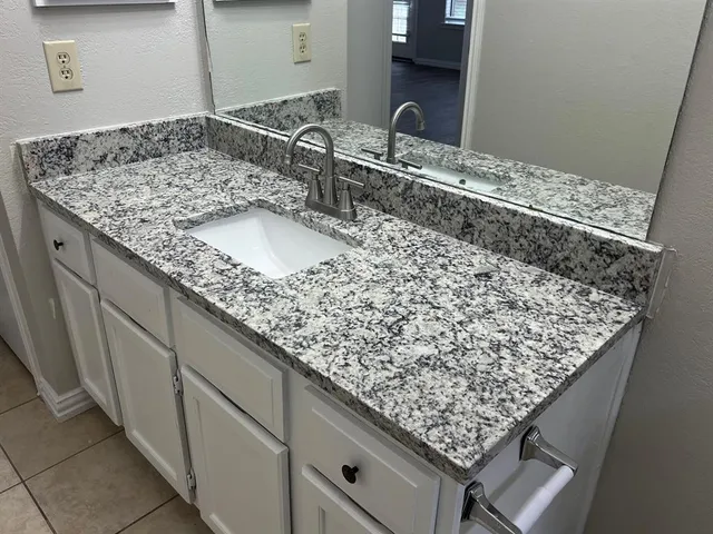 a bathroom with a granite countertop sink and a mirror