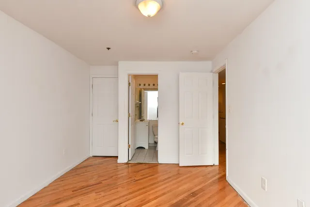 a view of an empty room with wooden floor and closet