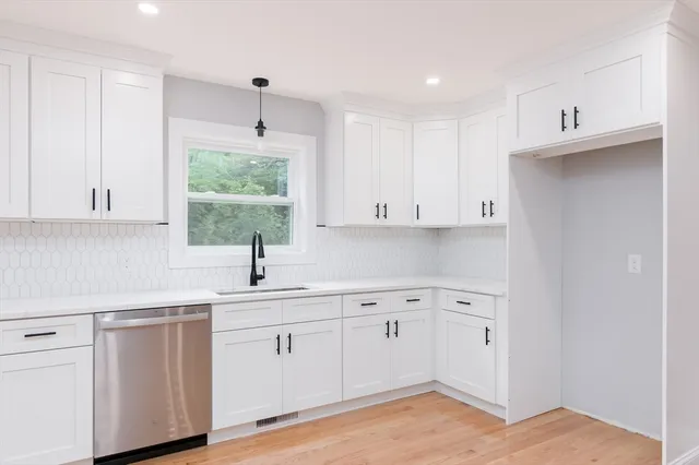 a kitchen with white cabinets appliances and a window