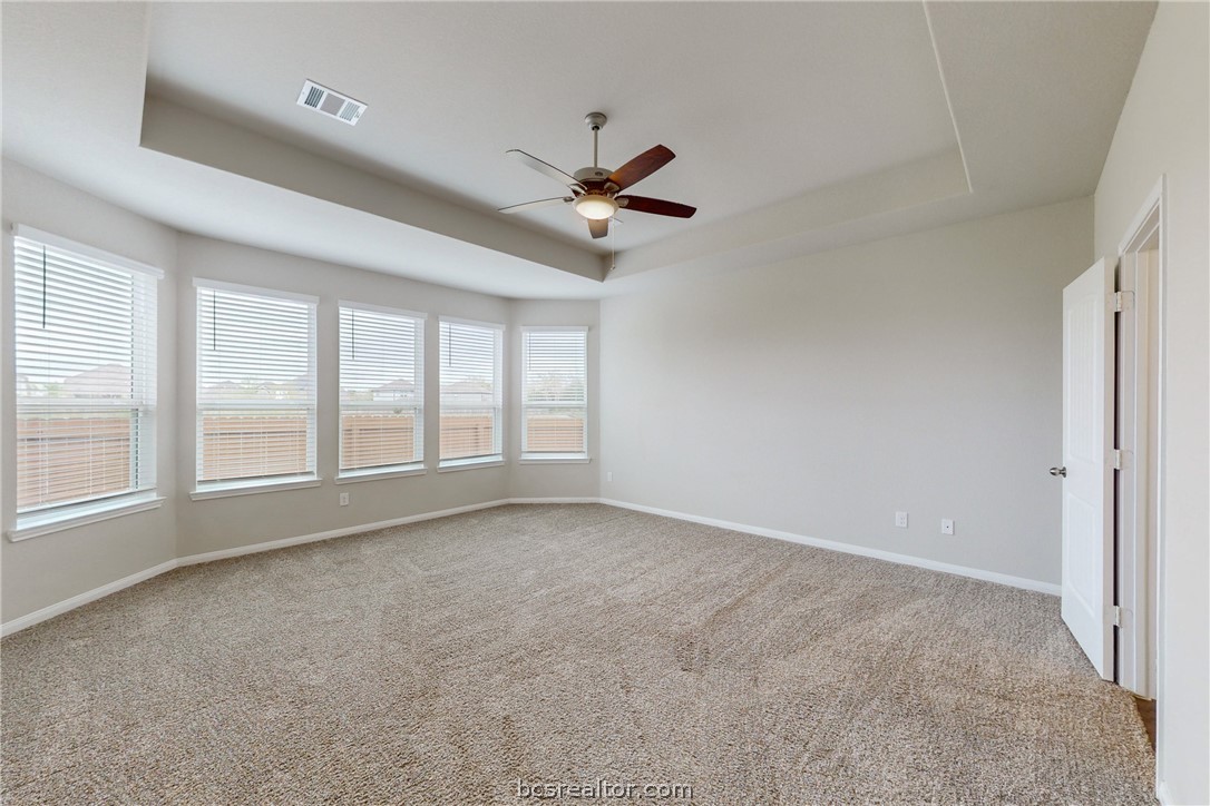 5764 Paseo Place Bryan, TX 77807 - Photo 10 of 35 Large primary bedroom with a large upgraded bay window that has a panoramic view of the backyard and green area behind it.
