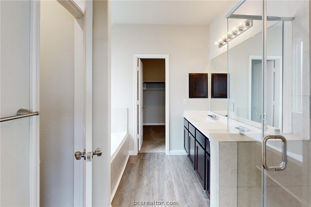 5764 Paseo Place Bryan, TX 77807 - Photo 12 of 35 Large en suite primary bathroom with a stand up shower, double vanity sinks, bath tub, large connecting walk in closet and enclosed water closet.