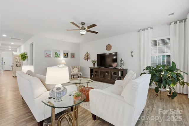 a living room with furniture a dining table with wooden floor and a flat screen tv