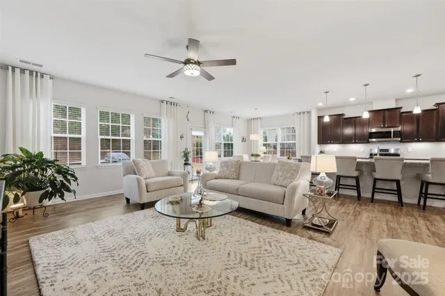 a living room with furniture kitchen view and large windows