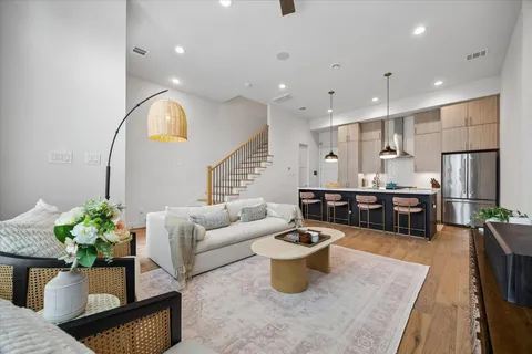a living room with furniture a potted plant and kitchen view