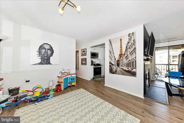 a living room with painting on the wall and wooden floor