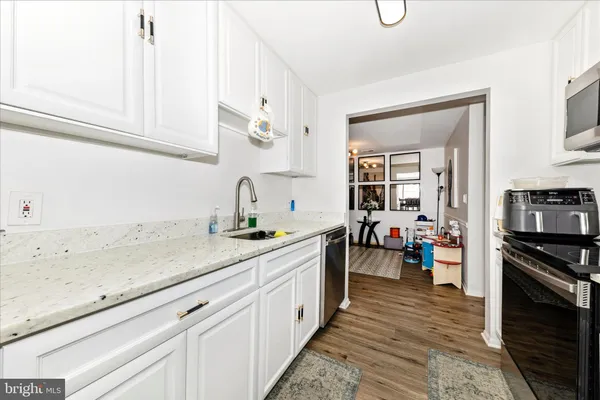a kitchen with a sink dishwasher stove and white cabinets