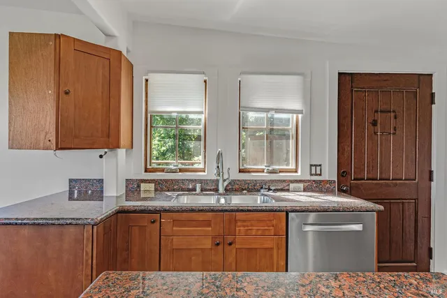 a kitchen with stainless steel appliances granite countertop wooden cabinets a sink and a dishwasher