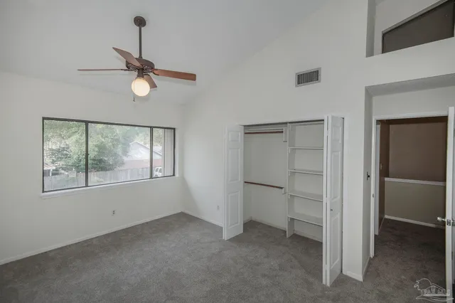 an empty room with windows and fan