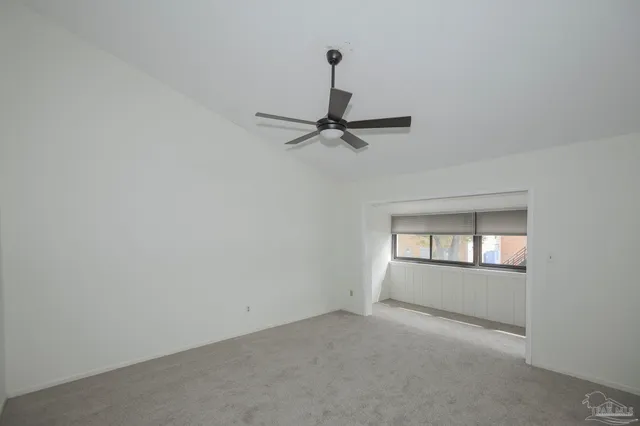 an empty room with chandelier fan and windows