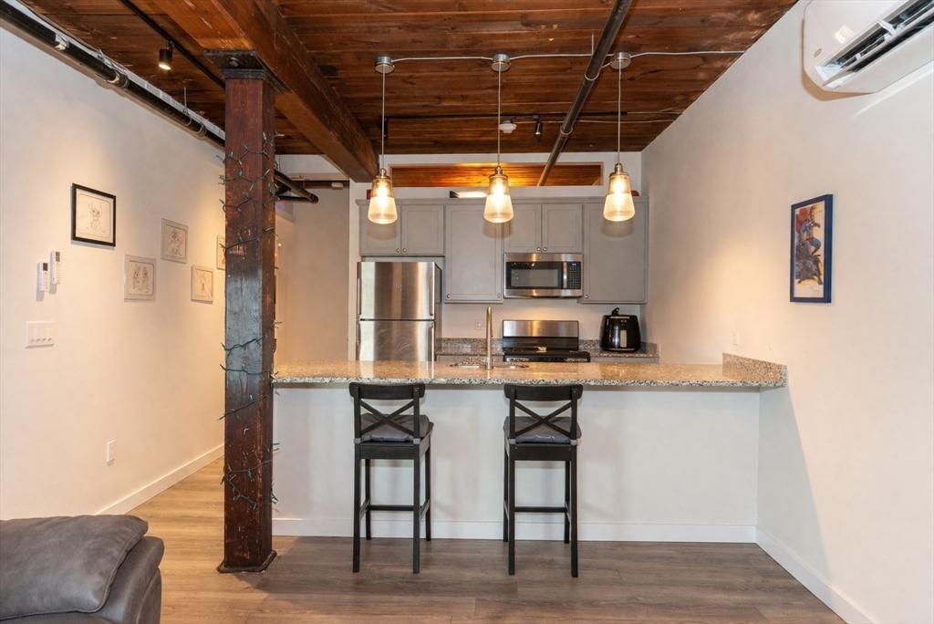 55 Sterling Street, Unit 305 Clinton, MA 01510 - Photo 3 of 31 a kitchen with stainless steel appliances a table and chairs in it
