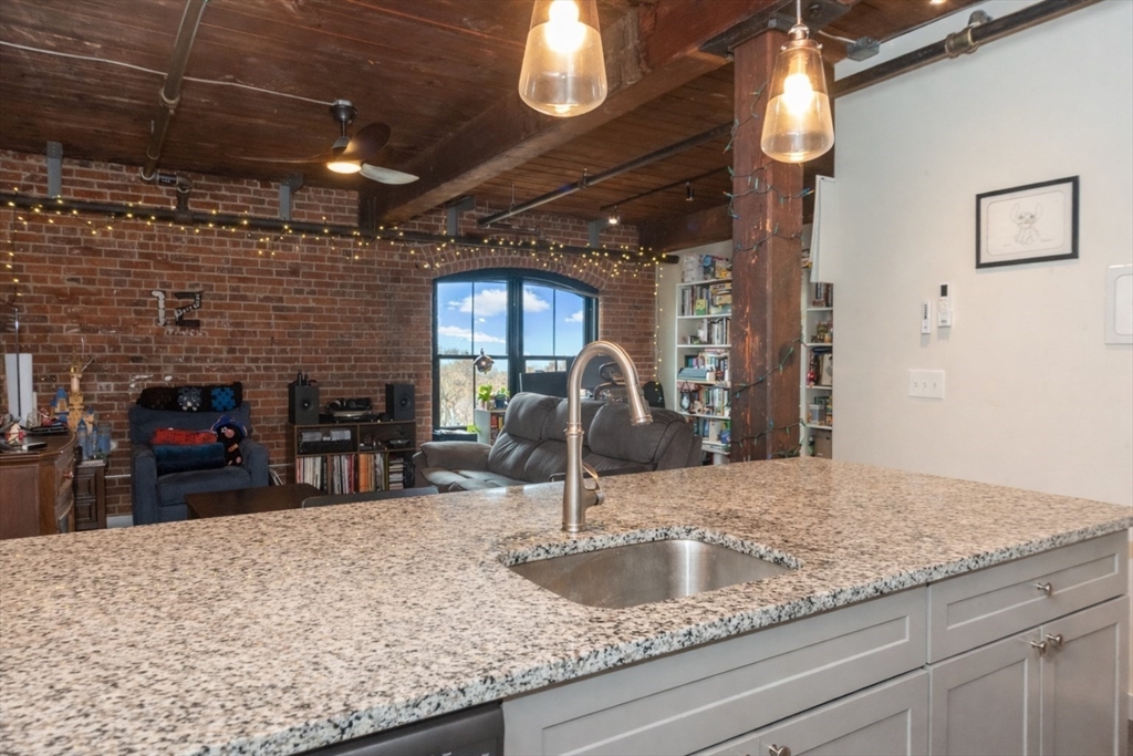 55 Sterling Street, Unit 305 Clinton, MA 01510 - Photo 5 of 31 a kitchen with kitchen island a sink granite counter tops and a view of living room
