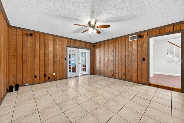 an empty room with windows and fan chandelier fan