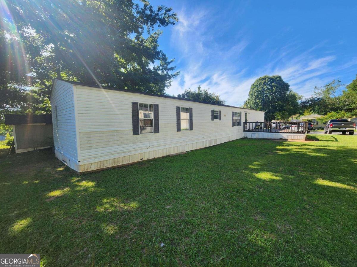 a backyard of a house with table and chairs plants and large tree