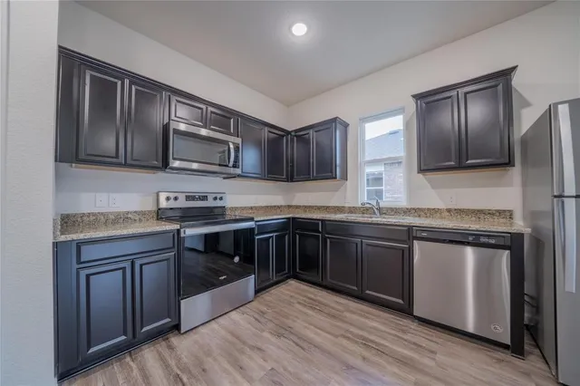 a kitchen with stainless steel appliances granite countertop wooden cabinets a stove top oven a sink and dishwasher