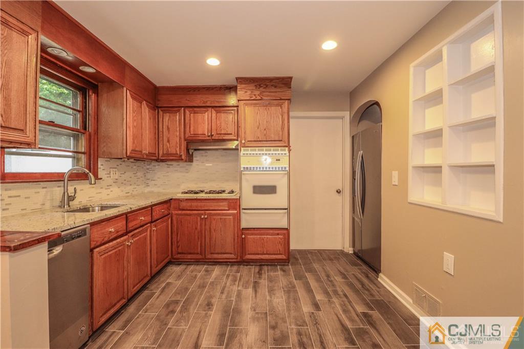20 Old Post Road Edison, NJ 08817 - Photo 5 of 25 a kitchen with stainless steel appliances granite countertop a refrigerator a sink dishwasher a stove and white countertops with wooden floor