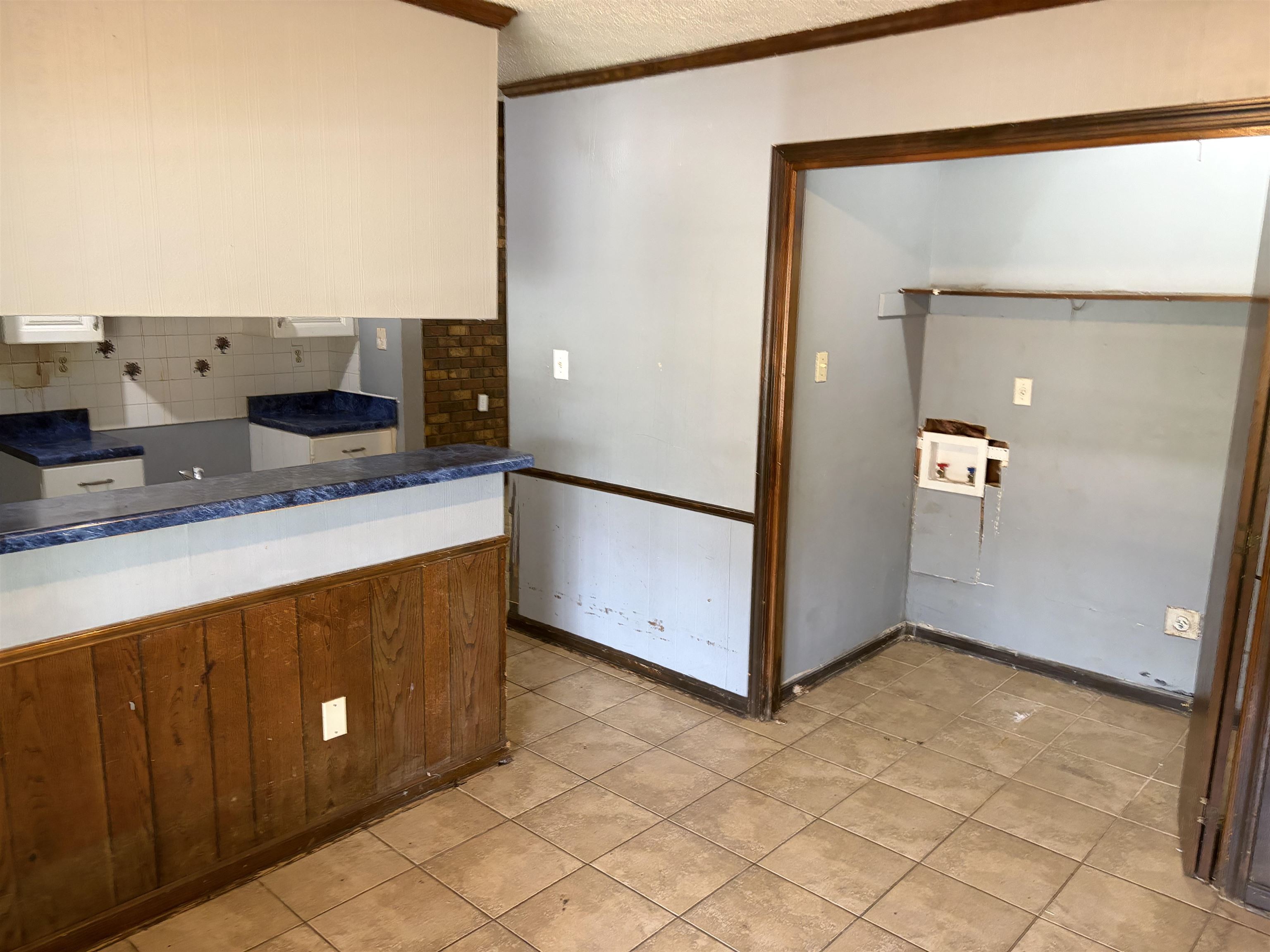 4993 Cedar View Road Memphis, TN 38118 - Photo 19 of 23 Kitchen area featuring a breakfast bar with wood paneling, blue countertops, white cabinetry, and a tile backsplash