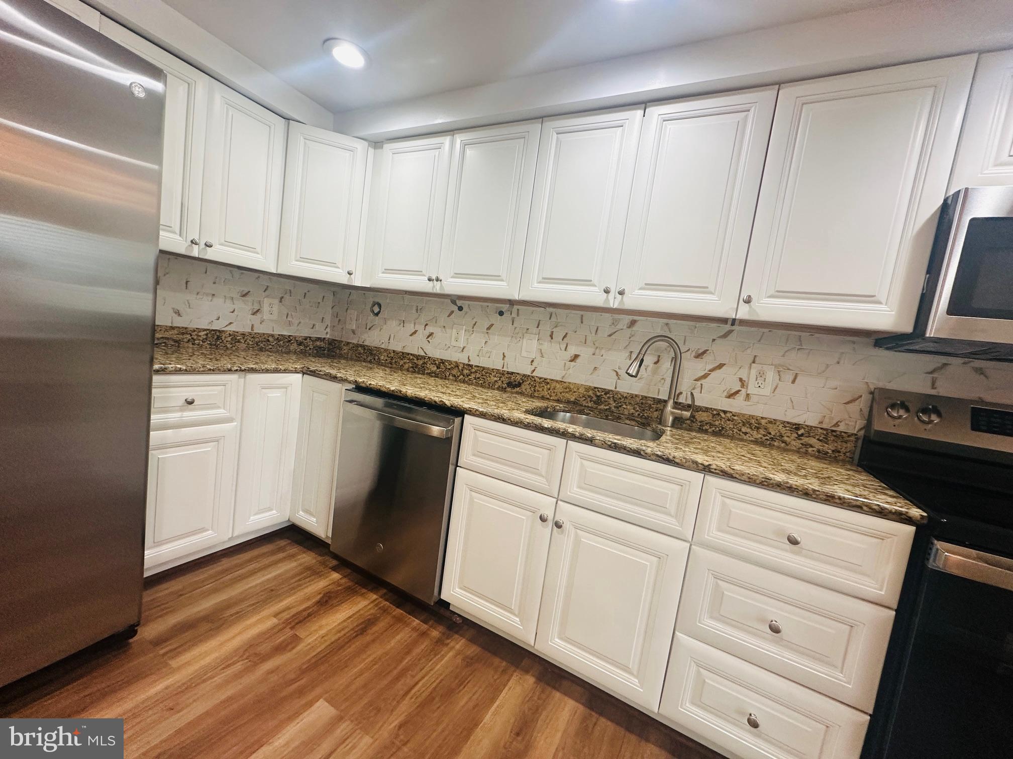 102 Hayloft Circle Sterling, VA 20164 - Photo 8 of 39 a kitchen with granite countertop white cabinets and white appliances